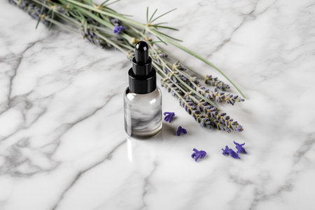 Lavender essential oil in a glass dropper bottle with fresh lavender flowers on white marble background. Natural cosmetic concept.の素材