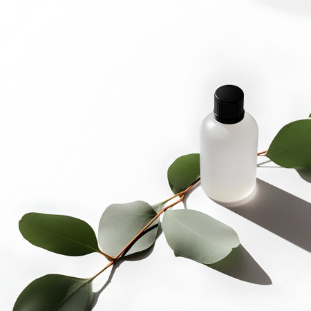 Mockup of cosmetic bottle with eucalyptus leaves on white backgroundの素材