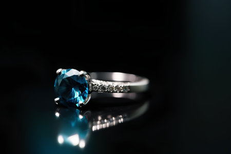 Engagement ring with blue sapphire on a black background.の素材