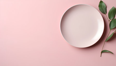 Empty plate and green leaves on pink background. Top view with copy space.の素材