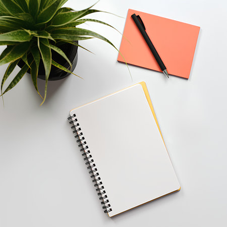 White office desk table with notepad, pen and plant. Top view with copy space. Flat lay.の素材