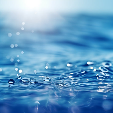 Water drops on blue water surface with sun rays and bokehの素材