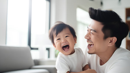 Happy asian family playing together in living room at home. Father and daughter smiling and having fun together.の素材