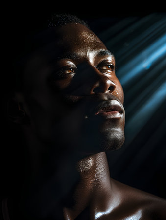 portrait of young african american man on black background with rays of lightの素材