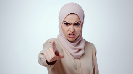 Portrait of a young muslim woman with hijab pointing at cameraの素材