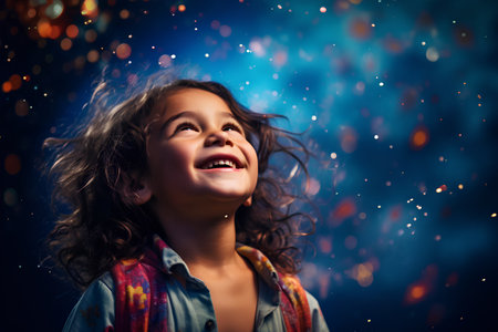 portrait of a happy little girl with long curly hair on a dark backgroundの素材