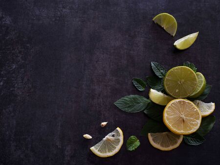Slices of lemon and lime with mint leaves on dark backgroundの写真素材