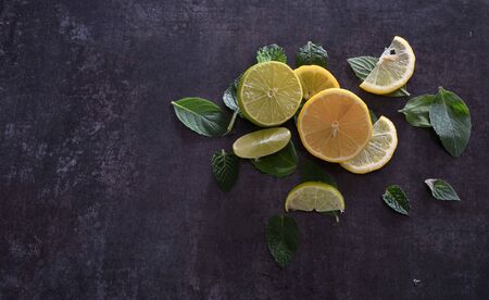 Slices of lemon and lime with mint leaves on dark backgroundの写真素材