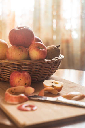 fall apple composition, basket filled with red and yellow apples, peeled apple it front, soft and warm light and colorsの写真素材
