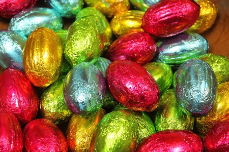 Stack of chocolate eggs in multi colored foils. Easter sweets