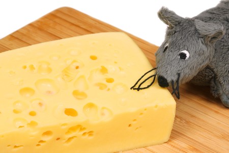 Grey plush mouse eating cheese on wooden boardの写真素材