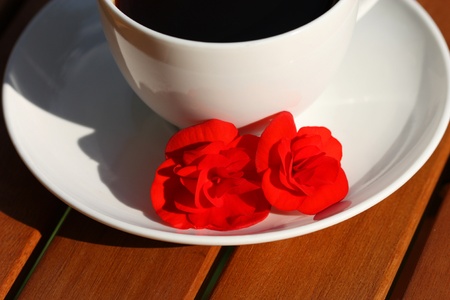 White cup of coffee and red flowersの写真素材