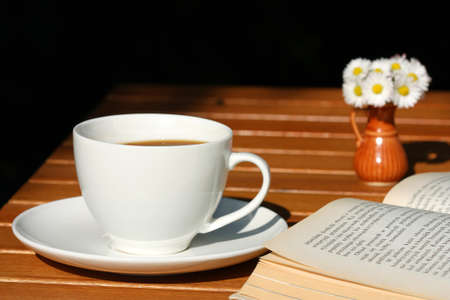 Coffee and book with beautiful daisies bouquet in small vaseの写真素材