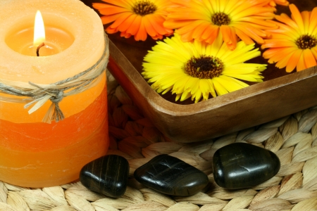 Spa in orange color: candle, calenula flowers and pebblesの写真素材