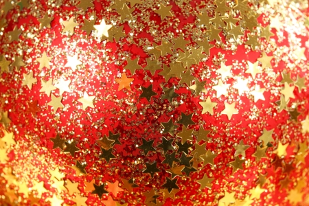Christmas gold shiny stars on red background. Macro of glass ballの写真素材