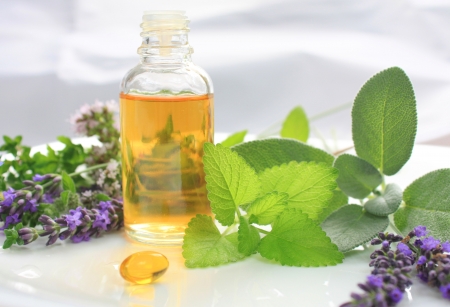 Closeup of oil bottle with fresh green herbs and aromatic flowers. Alternative medicine concept Closeup of oil bottle with fresh green herbs and aromatic flowers. Alternative medicine concept