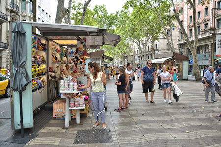 BARCELONA, SPAIN - AUGUST 08, 2014: People walk La Rambla street. La Rambla is popular tourist...