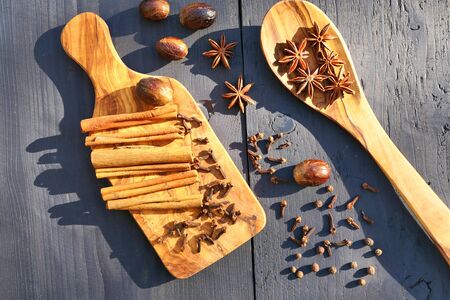 Aromatic spices on wooden board and spoon. Star anise, nutmeg, cloves, allspice and cinnamon sticksの写真素材