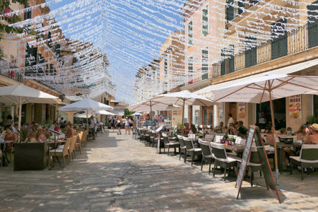 ALCUDIA, SPAIN -  AUGUST 10, 2019: Restaurant tables on street in seaside Alcudia old town, Mallorca island, Spain.のeditorial素材
