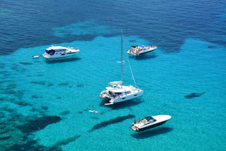 Turquoise water and floating boats in Cala D Hort bay on Ibiza island, Spain.のeditorial素材