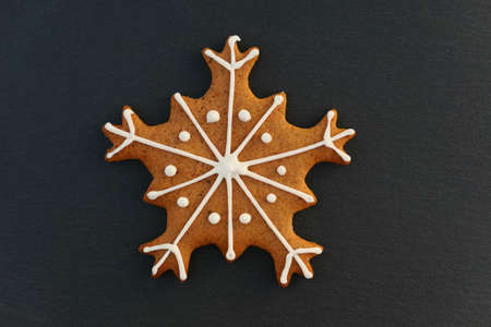 Snowflake gingerbread decorated Christmas cookie on black background.の写真素材
