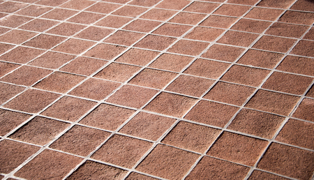 Sunlight shines on sandy colored floor pathway printed in perfect squares that outline white.