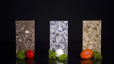 Three stone samples of kitchen cunter tops with food decoration on black tableの写真素材