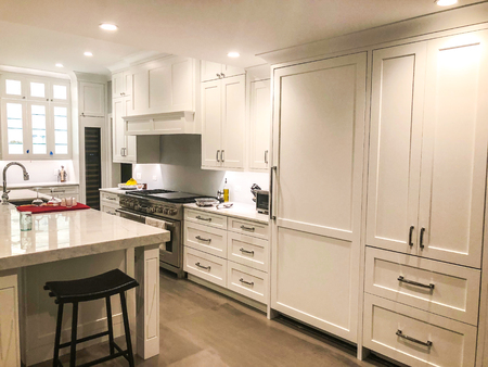 Kitchen tall and base cabinets made of wood and painted in white color with marble countertopの写真素材