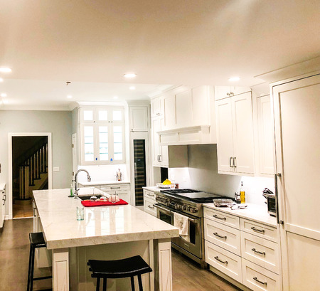 Modern white kitchen cabinets with a stainless steel appliances and island with white marble countertop and under mount sinkの写真素材