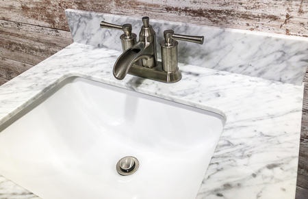Bathroom sink with white and gray granite cointertop and vintage look faucet with white and gray backsplashの写真素材