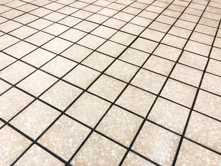 Beige square tiles plased straight with black grid like grout line, can be used as floor and wall tile, and can be used as kitchen countertop backsplashの写真素材