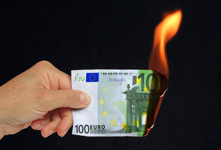 Burning euro banknote in hand on a black background close upの写真素材