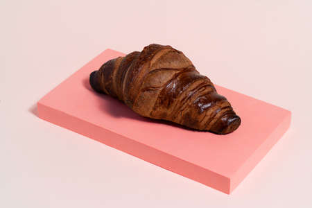 Fresh baked french croissant exposed on light pink background. Very tasty croissant ready to eat.の写真素材
