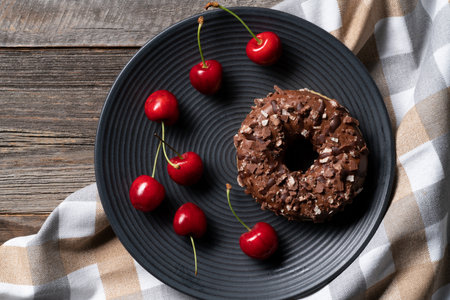 Freshly baked glazed donuts exposed on decorative platter with cherries scattered on the side....