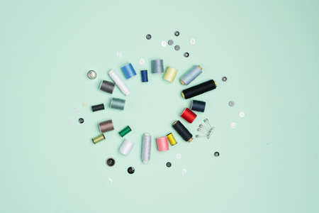 A lot of colorful spools of thread arranged on the green backgroundの写真素材