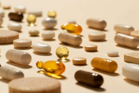 A close up image of medication pills arranged in a row on beige background