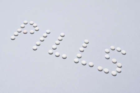 Pills sign made by small white painkillers on colorfull background