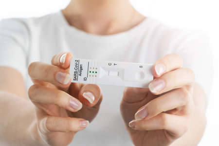 Close up image of woman's hands holding negative results of coronavirus test, on the white...
