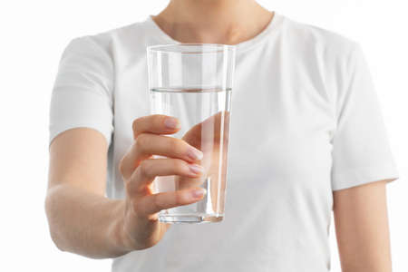 Close up image of woman holding in her hands clear glass of watter on white background