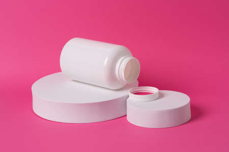 White bottle of medication with blank label for product presentation placed on white podium on the...