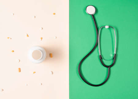 Top view of stethoscope, medication bottle and pills scattered all over the beige background. Medical equipmentの写真素材