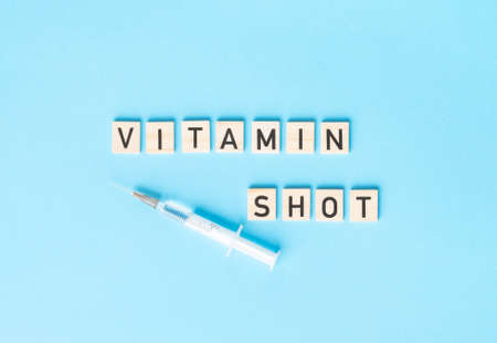 VITAMIN SHOT sign made by wooden cubes with syringe on the blue backgroundの写真素材