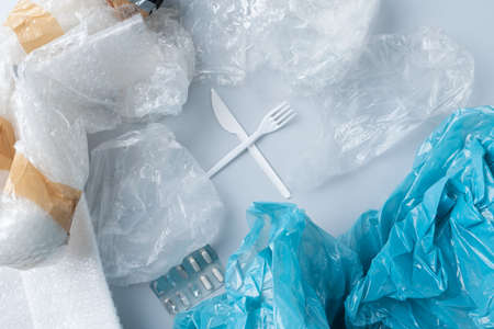 Top view of crossed plastic cutlery surrounded by plastic garbage.の写真素材