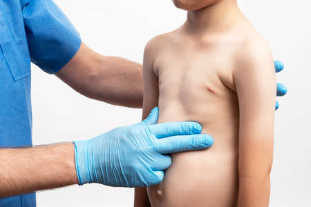 Male doctor examins little's boy body by making a routine check up
