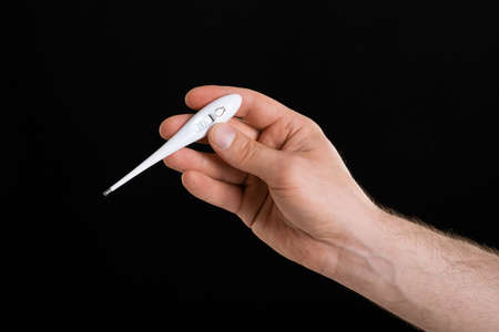 A close up image of man's hand holding a thermometerの写真素材