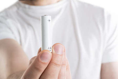 Close up image of mans hand holding battery on white background