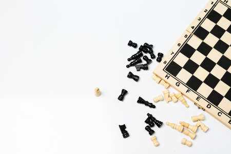 Top view of wooden chess board and chess pieces scattered on the white background.の写真素材