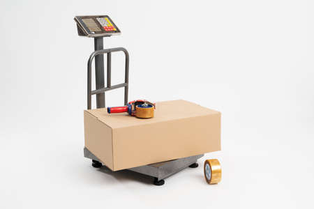 Industrial scale for weighing parcels for shipping with adhesive tape for packaging. Industrial scale isolated on whiteの写真素材