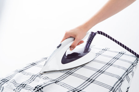 A Woman's ironing shirt with a modern steam iron. homeの写真素材