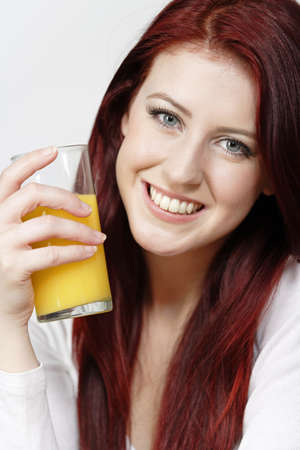 Smiling happy young woman with a fresh glass of Orange juice during breakfast.の写真素材